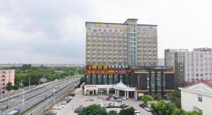 Un gran edificio con estacionamiento al lado de una autopista. en GreenTree Inn Shanghai Songjiang Xinqiao Jiuxin Road Express Hotel, en Chunshen