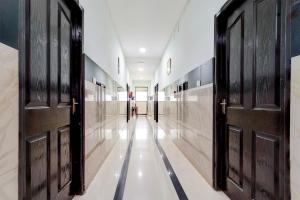 einen Flur mit schwarzen Türen und weißen Böden in der Unterkunft Hotel O Bharata Mata College Kakkanad in Kochi