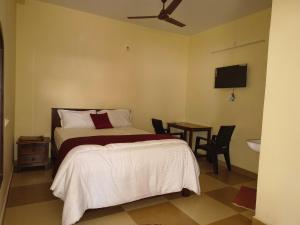 ein Schlafzimmer mit einem Bett und einem Tisch und einem Fernseher in der Unterkunft Layam Maison in Kuilapayam