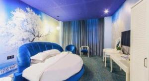 Un dormitorio con una cama azul y blanca y un televisor. en TO915101 STILL LOVE THEME HOTEL, en Chengdú