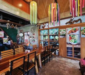a restaurant with a long wooden table and chairs at Maderlar Farm Restaurant & Resort in Ban Kao Lieo