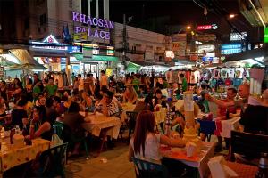 a crowd of people sitting at tables in a street at night at XX Mitr Khaosan Bangkok in Bangkok
