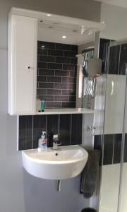 a bathroom with a white sink and a black tile wall at South Beach B & B in Lowestoft