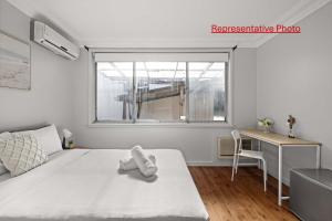 Un dormitorio blanco con una cama, un escritorio y una ventana. en Light & Simple Double Room - Peakhurst Area - Shared Bathroom, en Peakhurst