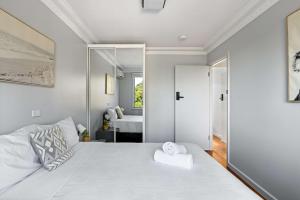 Un dormitorio con una gran cama blanca con espejo. en Light & Simple Double Room - Peakhurst Area - Shared Bathroom, en Peakhurst