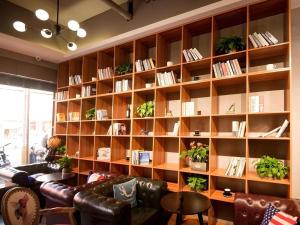 a living room with a couch and a book shelf at James Joyce Coffetel Xuzhou Feng County Huadi Street in Feng
