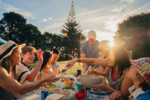 a group of people sitting around a table eating food at Tasman Holiday Parks - Papamoa Beach in Papamoa