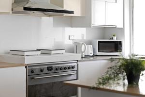a white kitchen with a stove and a microwave at Light & Simple Single Room - Peakhurst Area - Shared Bathroom in Peakhurst