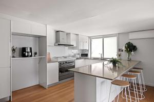 a white kitchen with a counter and stools in it at Light & Simple Single Room - Peakhurst Area - Shared Bathroom in Peakhurst
