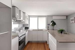 a kitchen with white cabinets and a large window at Light & Simple Single Room - Peakhurst Area - Shared Bathroom in Peakhurst
