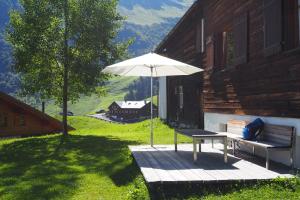 a bench and an umbrella on a porch with a house at Haus Glatthorn in Faschina