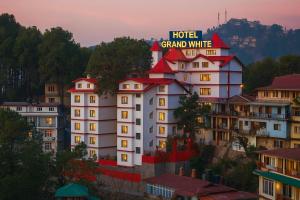 a hotel grand white with a sign on top of it at The Grand - A Premium Hotel near new BUS STAND SIMLA- Centrally heated in Shimla +16 photos