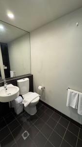 a bathroom with a toilet and a sink and a mirror at One Bedroom Penthouse Apartment in the heart of Box Hill in Box Hill