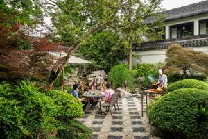 a group of people sitting at tables in a garden at Four Seasons Hotel Hangzhou at West Lake in Hangzhou