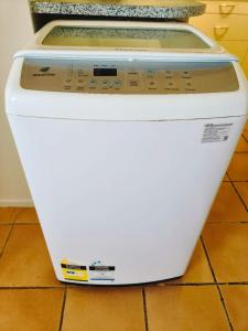 a white washing machine sitting on a tile floor at Bayview Holiday Flat in Auckland +5 photos