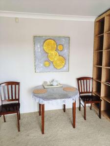 a table with two chairs and a painting of lemons at Bayview Holiday Flat in Auckland