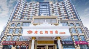 a tall building with a sign in front of it at Vienna Hotel Jiangsu Kunshan Changjiang North Road Fenghuangcheng in Kunshan