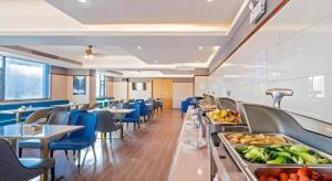 a restaurant with tables and blue chairs and a buffet at Gya Hotel Zhuhai International Airport New Town in Baigaonongchang