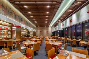 una sala da pranzo con tavoli e sedie in legno di Angsana Xi'an Lintong a Lintong