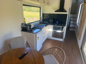 a small kitchen with a table and a table and chairs at Ferncroft Farm Tiny Home Berry in Wattamolla
