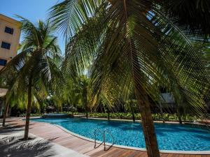 a swimming pool with palm trees next to a building at NARITA Classic Hotel in Surabaya