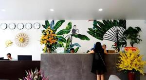 a woman standing at a counter in a room with plants at Green Oasis Hotel in Phường Sáu