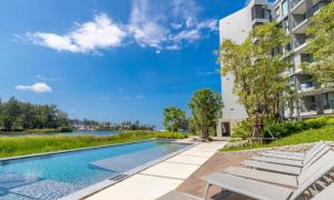 uma piscina com espreguiçadeiras ao lado de um prédio em Cassia Exclusive Lake View Condo Bang Tao Beach em Laguna Phuket