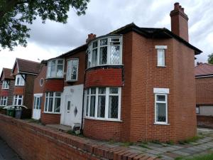 a red brick house with white windows on a street at Old Trafford Guest House in Manchester