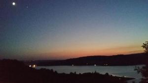 una vista di un lago di notte con la luna di Poggio San Giacomo a Baschi