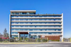 Un edificio de oficinas con un estacionamiento enfrente. en Wyndham Concepcion Pettra, en Concepción