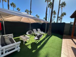 a patio with a tent and chairs and palm trees at Mar y Sol in Maspalomas