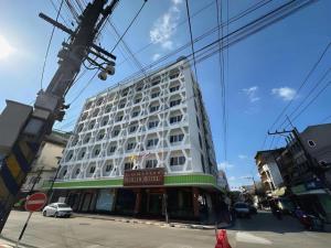 Un gran edificio blanco en la esquina de una calle. en Merlin Hotel, en Sungai Kolok