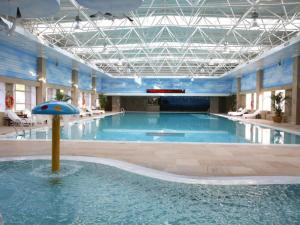 uma grande piscina com um guarda-sol no meio em Grand Mercure Teda Dalian em Dalian