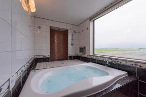 a large tub in a bathroom with a large window at HOTEL C-L'esapce in Honjo