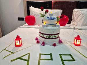 um bolo de casamento em uma cama com velas e luzes em Alimas Holiday Retreat Maldives em Felidhoo