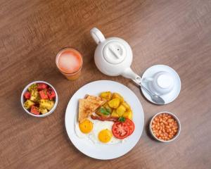 un tavolo con un piatto di cibo per la colazione e una teiera di Entebbe Hotel a Entebbe
