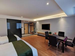 a hotel room with two beds and a desk and a television at GreenTree Inn Ganzhou Gan County Bus Station in Meilin