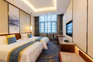 a hotel room with two beds and a flat screen tv at YUN-RAY Hotel Shijiazhuang in Zhufutun