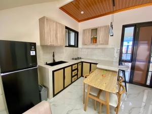 uma cozinha com um frigorífico preto e uma mesa em Sierra Villa Malang - Private Swimming Pool - 4 BR em Ngadipuro