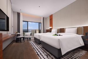 a hotel room with four beds and a television at Yuezhi Hotel Longnan Yingbin Avenue Branch in Magutang