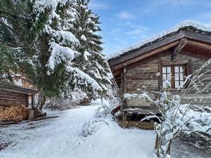 uma cabana de madeira com neve nos galhos das árvores em Happiness only! em Bruson