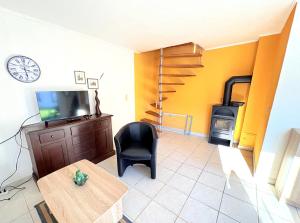 a living room with a tv and a chair and a table at Ferienhaus Nele - ein strandnahes, einfaches Haus in Breege