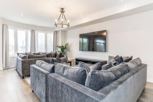 ein Wohnzimmer mit einem großen Sofa und einem Fernseher in der Unterkunft Modern Luxury Townhome Walk to Blue Shuttle in Blue Mountains + 61 Fotos