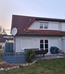 Ferienhaus zum Kranichblick في Garz: بيت ابيض ومقعد امامه