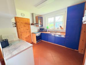 a kitchen with blue cabinets and a sink and a window at Ferienhaus zum Kranichblick ideal für Familien gern mit Hund in Garz