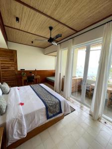 a bedroom with a bed and a large window at Bayview Gardens Hotel in Labuan Bajo