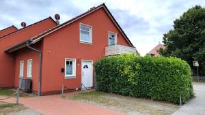 a red house with a bush in front of it at Ferienhaus Carlo - renoviert 2025, top Lage, hundefreundlich in Glowe