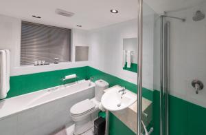 Historic Mutual Heights CBD Loft w Pool & Gym في كيب تاون: حمام اخضر وبيض مع مرحاض ومغسلة +9 صور