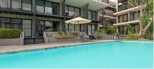 Historic Mutual Heights CBD Loft w Pool & Gym في كيب تاون: مسبح امام مبنى فيه مظله