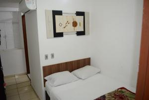 a small room with a bed and a clock on the wall at Lize Hotel in Campinas